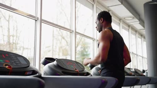 Fit Man Exercising on a Running Machine at the Gym