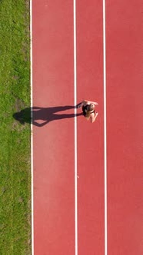Top View Of Young Woman Running On Red Athletic Track At Stadium