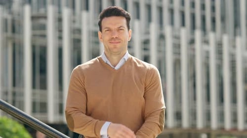 Man Smiling with Arms Crossed Near Office Building