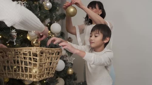 Family Decorating Christmas Tree with Golden Ornaments