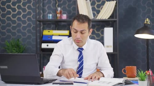 Man Working at Desk Looks Tired and Bored