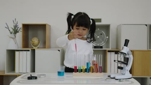 Estudio científico de una niña pequeña utilizando una pipeta para dejar caer líquido con un tubo de ensayo y un vaso de precipitados