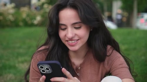 Young Woman Using Smartphone in a Park