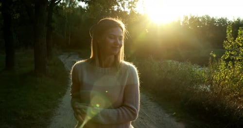 Woman in Sweater Smiling at Sunrise in Forest