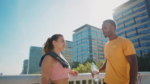 Athletic Woman and Man Drinking Water in City
