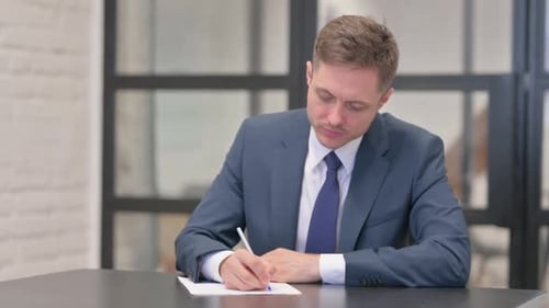 Young Businessman Writing a Letter in Office