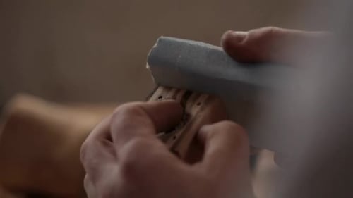 Carpenter sanding wood block with sandpaper in his calgary alberta workshop