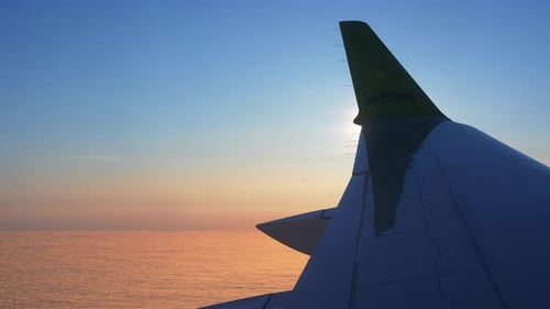 A Plane Flying Above the Clouds at Sunset