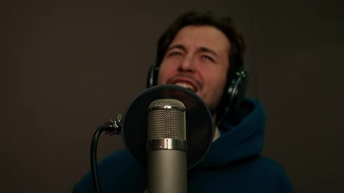 singer with headphones and microphone emotionally recording a new song in a professional studio