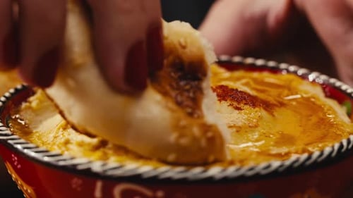 Dipping Flatbread into Bowl of Hummus