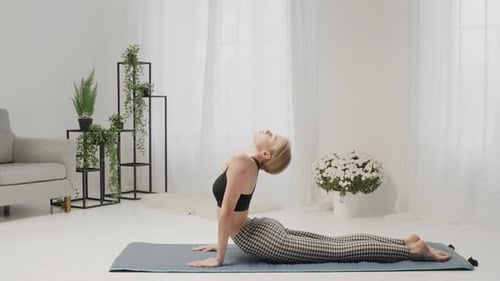 Blonde Woman Practicing Yoga on a Mat at Home