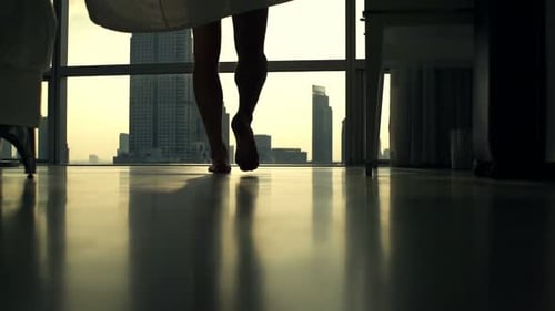 Man Undresses in Apartment Overlooking City at Sunset