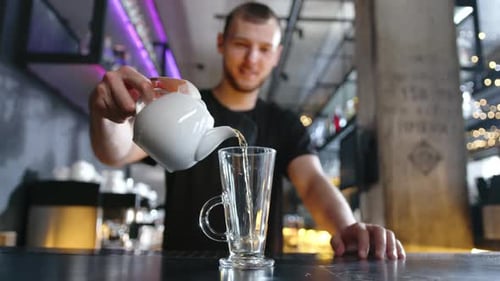 Barista Pours Hot Tea Into a Glass on the Bar Counter