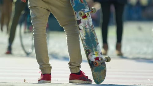 Young Adult Holding Skateboard in Urban Setting