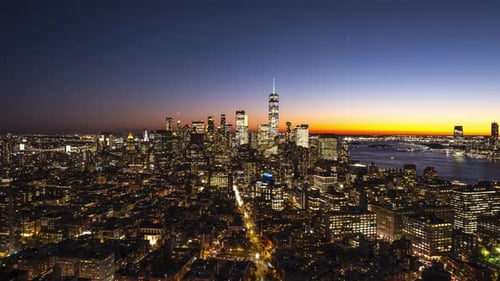 Un timelapse aérien capture la transition du ciel du bleu au noir alors que la nuit enveloppe Manhattan