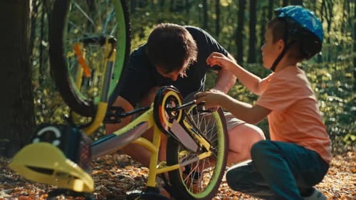 Man and Child Repairing Bicycle in Forest