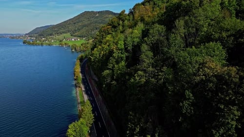Road Along The Lake By Forested Mountain In Summer. - aerial shot