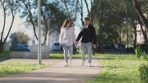 Young Couple Holding Hands While Walking in a Park