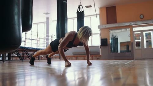 Young muscular woman doing pushups at the gym. Careful warm-up before training, exercise exercises