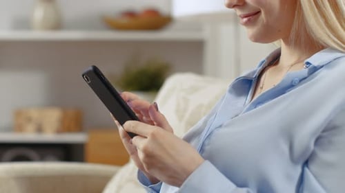 Close-up Of a Woman at Her Home Sitting on a Sofa and Using Her Smartphone.