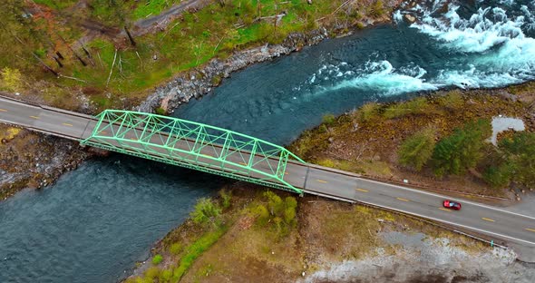 Red car rides by the road and crosses the bridge over quick river ...