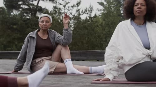 Women Doing Yoga Poses on Wooden Platform