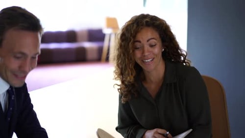 Diverse business professionals smile while discussing project paperwork in modern office