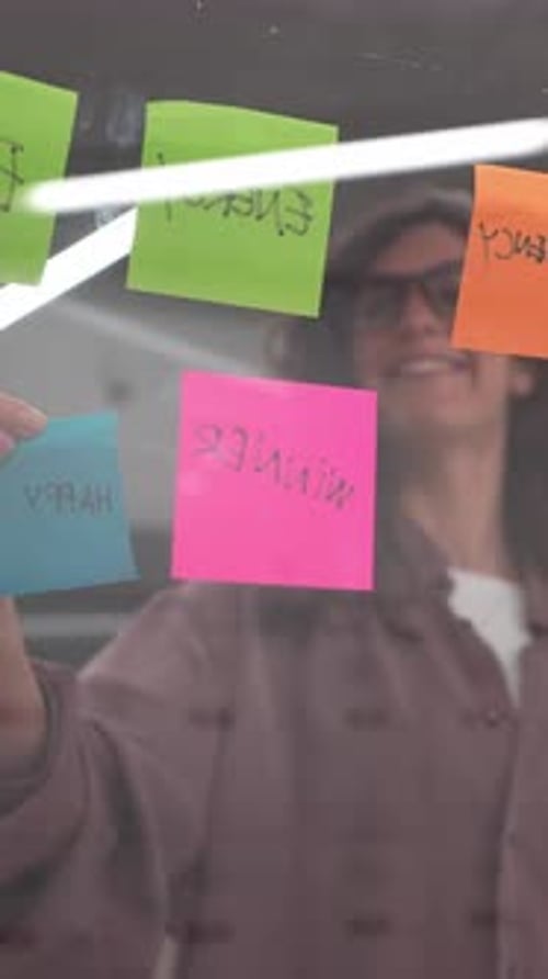 Young Woman Attaching Sticky Notes on Glass Wall in Slow Motion