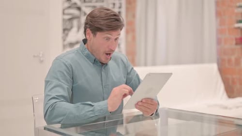 Man Using Tablet Excited by News Indoors