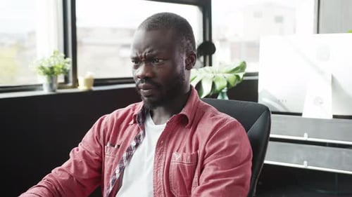Man Grimaces While Typing in Office Setting
