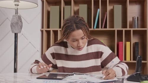 Woman Works at Desk with Tablet and Graphs