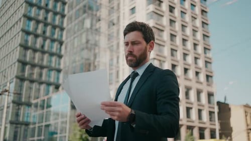 Bearded Man in Suit with Papers on City Street