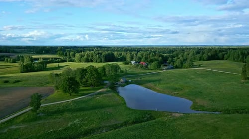 Aerial drone view of a countryside farm with a pond and beautiful sky