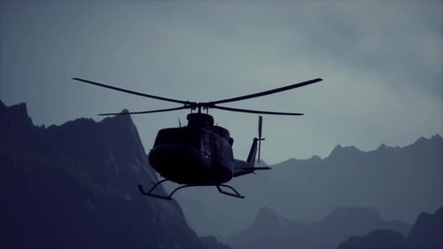 Un helicóptero negro sobrevolando una cadena montañosa