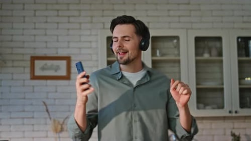 Cheerful Man Dancing in Kitchen with Headphones