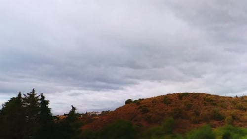 Time lapse of dark clouds passing by a hill