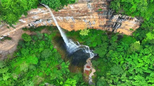 Aerial view: Majestic waterfall cascades from cliff.
