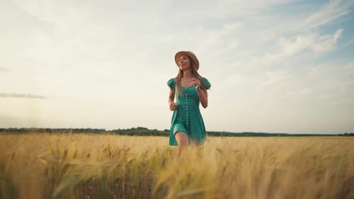 Carefree Happy Joyful Woman in Straw Hat Dress Running on Wheat Field at Cloudy Summer Day Feeling