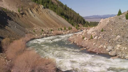 Fast River Flowing Through Rocky Mountain Valley Under Clear Sky