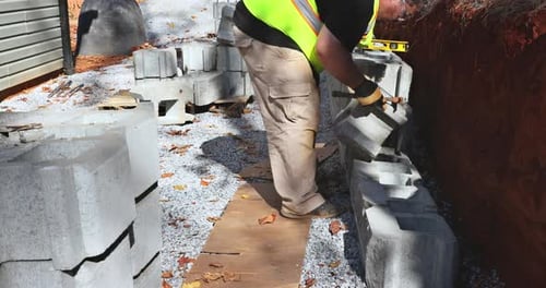 On the Construction Site of a New Large Block Retaining Wall a Contractor Was Seen Installing the