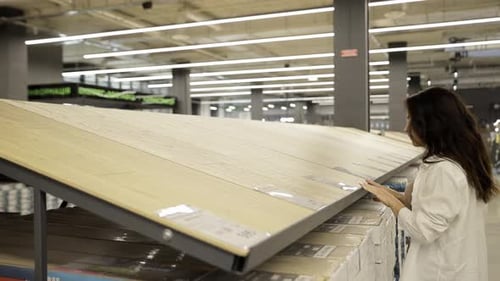A Young Woman Examines a Laminate Floor in a Hardware Store