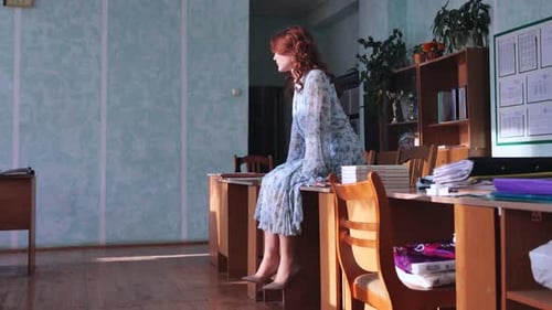 Woman Sitting on Desk in Classroom