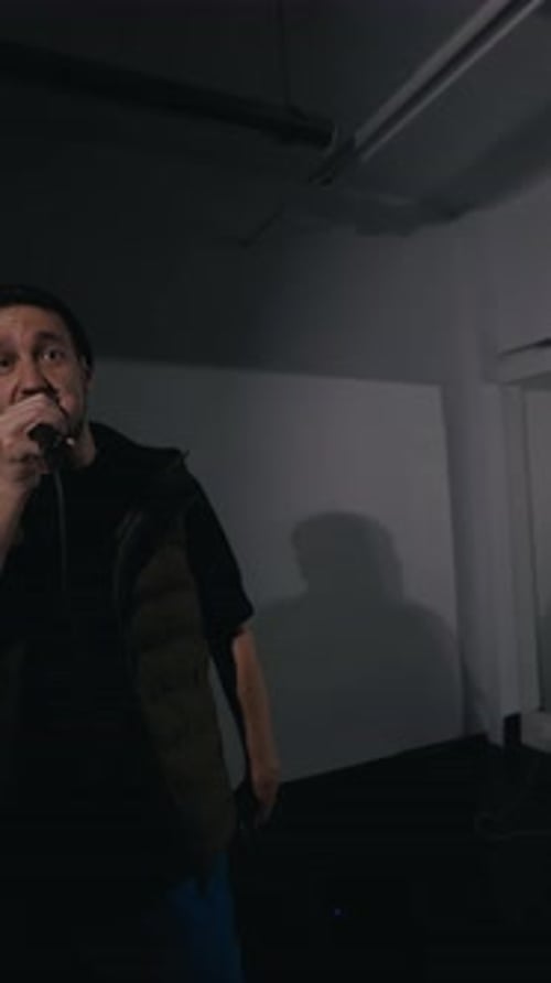 Man Sings Into Microphone During Dark Performance