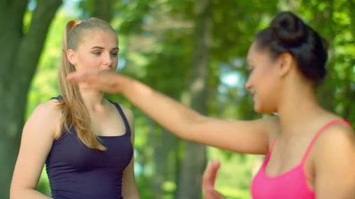Frauen sprechen im Park. Zwei schöne Mädchen unterhalten sich im Freien. Fitnessfrau spricht im Freien. Zwei Gi...