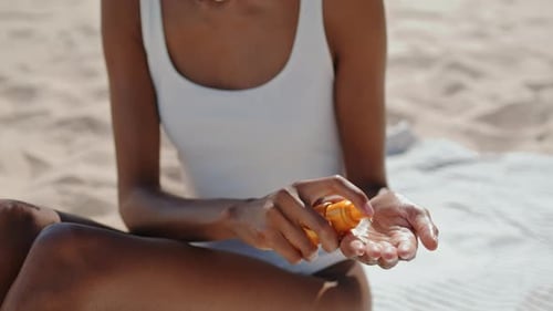 Spray pour les mains, huile de protection solaire, gros plan. Jolie fille prenant un bain de soleil au bord de la mer. Mince
