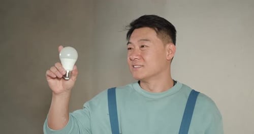 Adult Holding LED Light Bulb Indoors