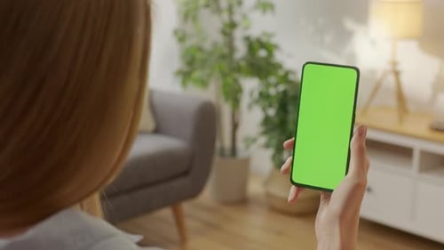 Back View of Woman Holding Chroma Key Green Screen Smartphone Watching Content Without Touching or