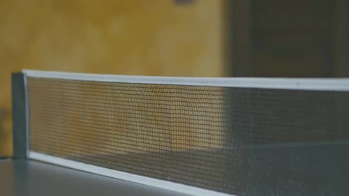 Slow motion of a ping pong ball hitting the net during a match, detail of the net while the rest of