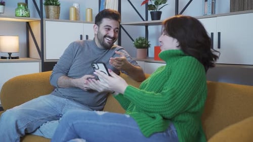 Couple Smiling and Laughing Looking at Phones Together