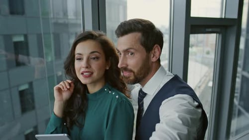 Cheerful business couple joyfully talking after meeting in modern city office